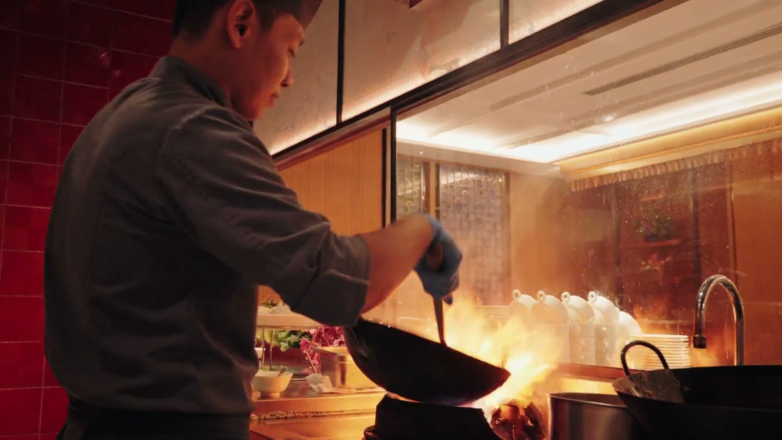 Standbild aus dem TasWiq-Showreel: Koch am Wok mit Flammen